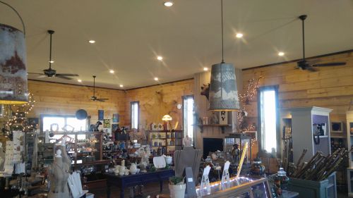 A cozy shop interior with wooden walls, decorative items, and warm lighting, featuring various crafts and home goods.