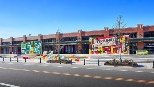 Colorful murals adorn a brick building with steps leading up, under a clear blue sky.