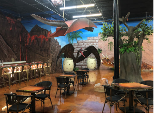 A themed restaurant interior featuring dinosaur decorations, large eggs, and a vibrant mural of a prehistoric landscape.