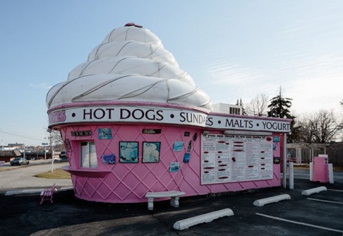 A whimsical ice cream-shaped food stand featuring a menu for hot dogs, sundaes, malts, and yogurt.