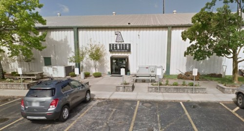 Exterior view of the Zenith Climbing Center, featuring a large building with a logo and parking area.