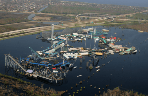 Aerial view of a flooded amusement park, with rides partially submerged in water and surrounding roads visible.