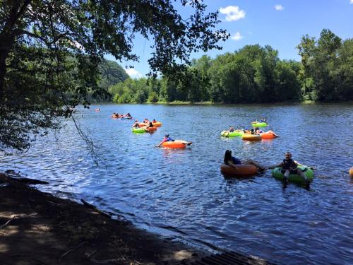 People floating on colorful inflatable rafts in a calm river surrounded by lush green trees under a clear blue sky.