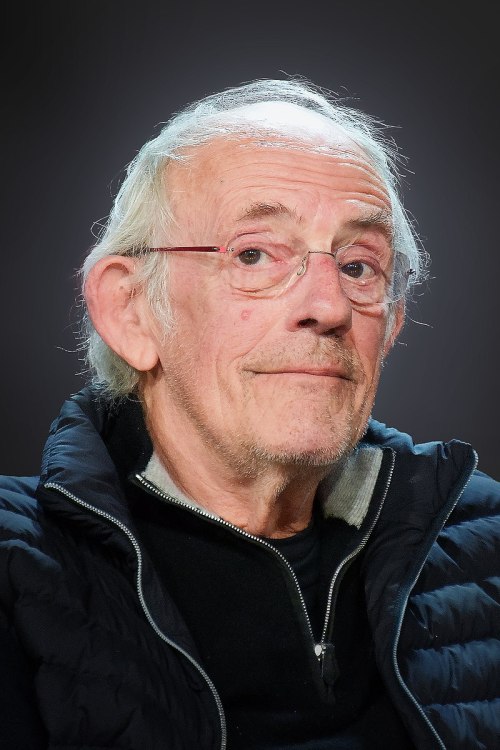 An older man with glasses and gray hair, wearing a black jacket, looking thoughtfully at the camera.