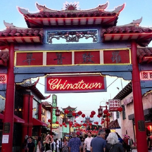 Entrance to Chinatown with a red archway, lanterns, and people walking through a vibrant street.