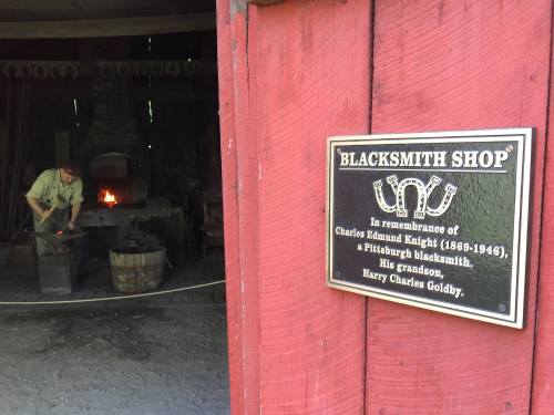 A blacksmith shop entrance with a plaque honoring Charles Edmund Knight and his grandson, Harry Charles Goldby.