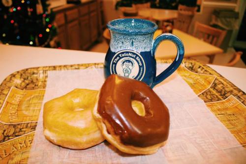 A tray with two donuts, one glazed and one chocolate, alongside a blue mug in a cozy kitchen setting.
