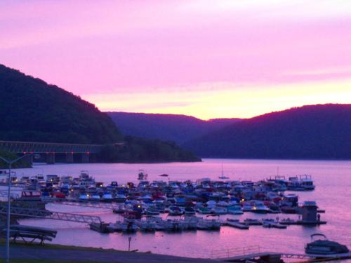 A serene marina at sunset, with boats docked and mountains silhouetted against a colorful sky.