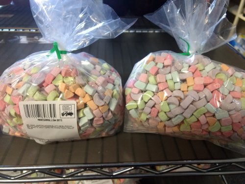 Two clear bags filled with colorful, small, square-shaped candy pieces in pastel shades.