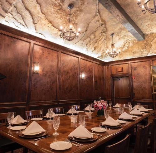 Elegant dining room with a wooden table set for a meal, featuring chandeliers and a textured ceiling.