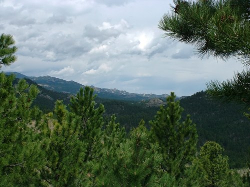 A scenic view of mountains and dense green trees under a cloudy sky.