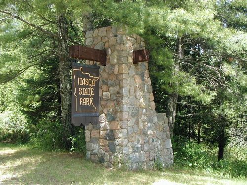 Stone entrance sign for Itasca State Park, surrounded by trees and greenery.
