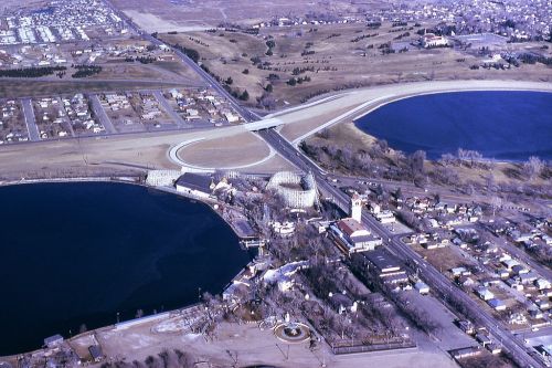 Aerial view of a landscape featuring two lakes, a highway, and a small town with residential areas and parks.