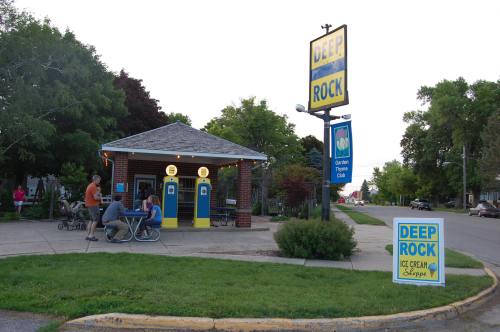 A small ice cream shop with outdoor seating, surrounded by trees and a sign for "Deep Rock Ice Cream Shoppe."