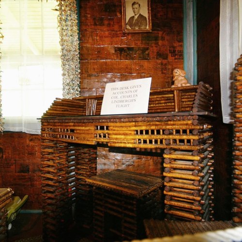 A rustic wooden display with a sign, set in a room with natural light and framed photos on the walls.