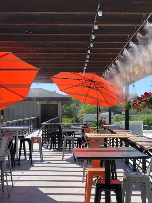 Outdoor dining area with orange umbrellas, misting system, and string lights, creating a vibrant and inviting atmosphere.