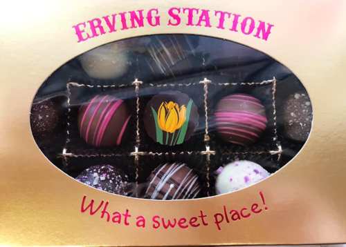 A box of assorted chocolates with a decorative flower design, labeled "What a sweet place!" on a golden background.