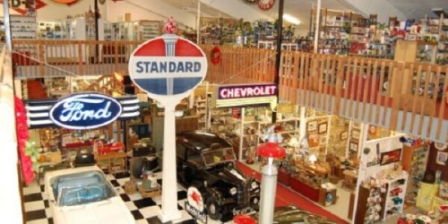 A vintage car museum featuring classic cars, memorabilia, and retro signage from Ford and Chevrolet.