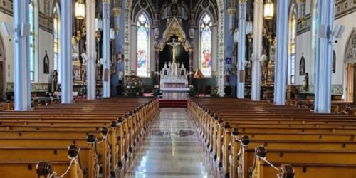 Interior of a grand church featuring wooden pews, stained glass windows, and an ornate altar at the front.