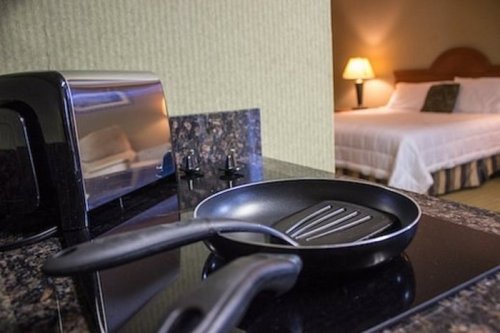 A kitchen countertop with a frying pan, toaster, and a blurred view of a hotel room in the background.