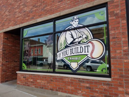 Window display featuring a baseball theme with the text "If You Build It" and an illustration of a player.