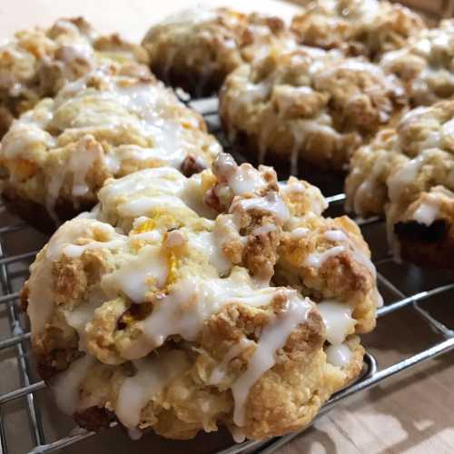 Close-up of freshly baked cookies drizzled with white icing, resting on a cooling rack.