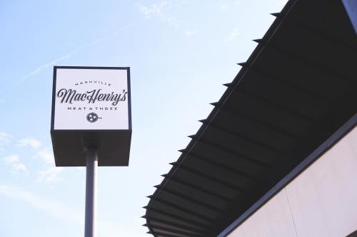 Sign for MacHenry's Meat & Three in Nashville, featuring a clear blue sky and a modern building design.