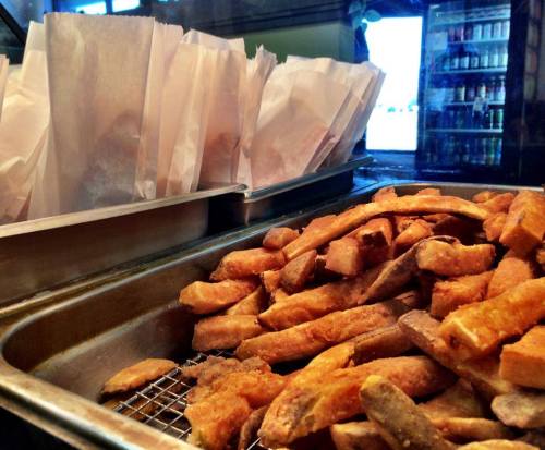 A tray of golden-brown fried potatoes with paper bags in the background, ready for serving.