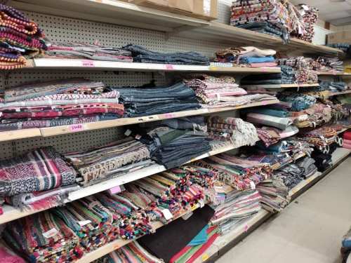 Shelves filled with colorful textiles and blankets in a store, showcasing various patterns and textures.