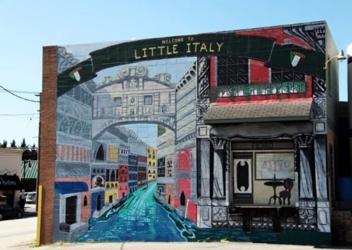 Colorful mural depicting a vibrant Little Italy scene with buildings, a canal, and welcoming signage.