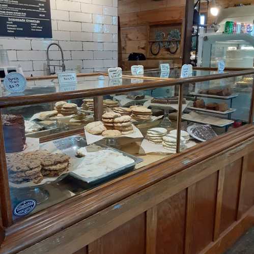 A display case filled with various baked goods, including cookies, cakes, and pastries in a cozy café setting.