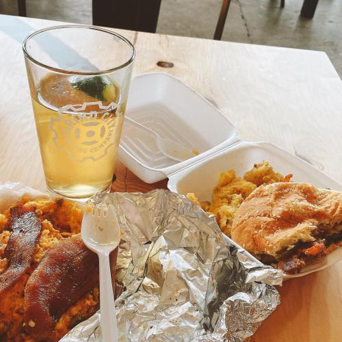 A meal featuring a sandwich, scrambled eggs, and a drink on a wooden table.