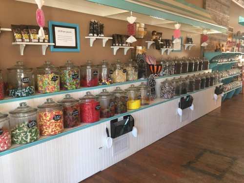 A colorful candy shop display with jars of various candies on shelves, featuring a bright and inviting atmosphere.