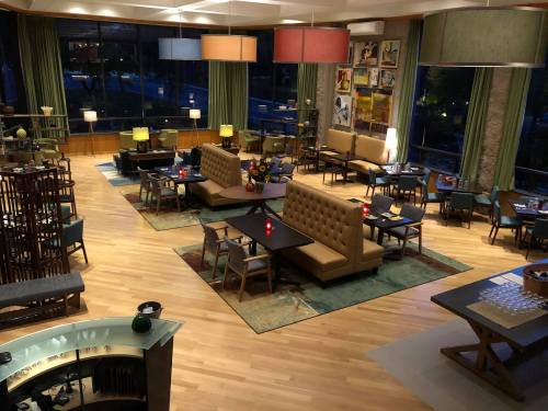 A spacious, modern lounge with wooden floors, cozy seating, and large windows, illuminated by stylish lamps.