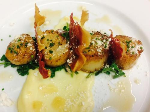 Seared scallops on a bed of greens, topped with crispy prosciutto and drizzled with sauce, served with creamy puree.