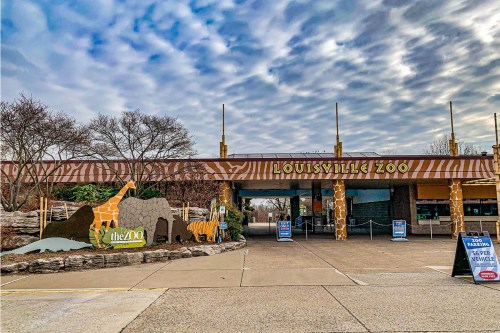 Entrance to the Louisville Zoo featuring animal sculptures and a cloudy sky.