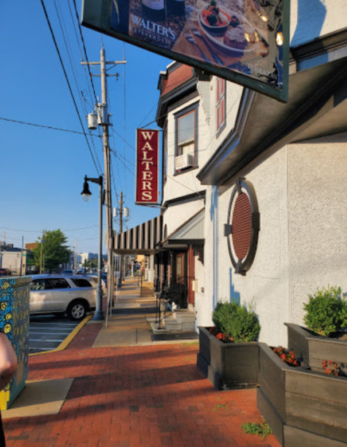 A street view of a building with a sign reading "Walter's," featuring outdoor seating and planters along the sidewalk.