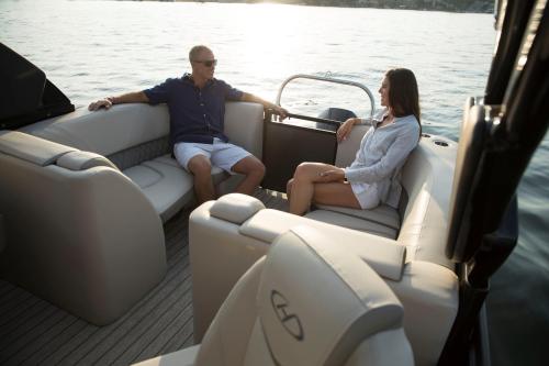 Two people relax on a boat, enjoying the water and sunset, seated on comfortable cushions.