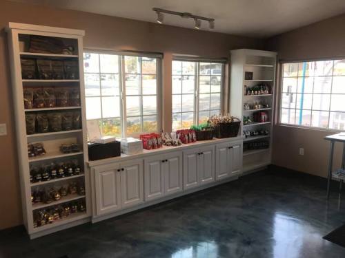 A cozy shop interior with shelves displaying various snacks and treats, illuminated by natural light from large windows.
