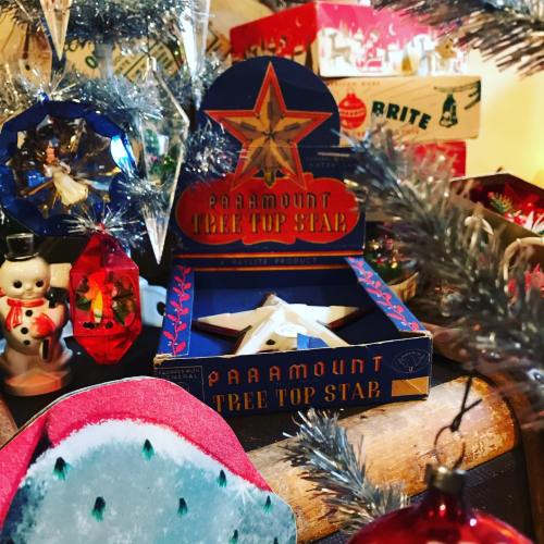 A vintage Paramount Tree Top Star box displayed among colorful ornaments and decorations on a Christmas tree.