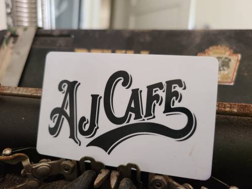 A close-up of a card with the text "AJ CAFE" displayed on an old typewriter.