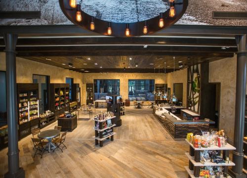 A spacious, modern retail store with wooden floors, shelves of products, and a cozy seating area.