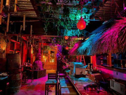 A vibrant, tropical-themed bar with colorful lighting, bamboo decor, and lush greenery.