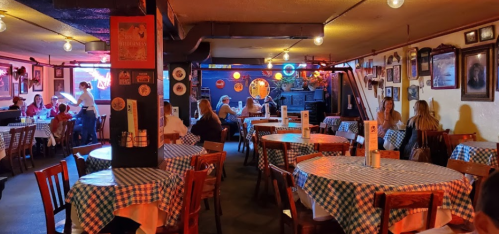Cozy restaurant interior with checkered tablecloths, dim lighting, and patrons enjoying their meals.