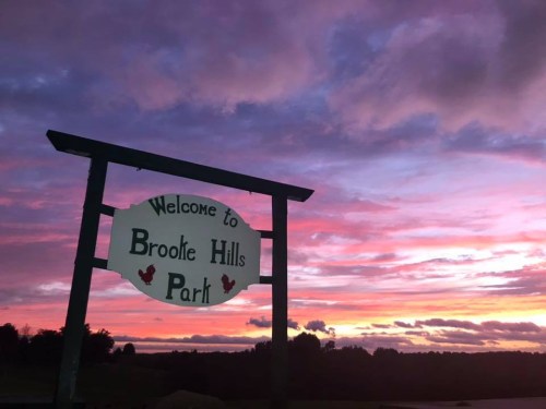 Sign welcoming visitors to Brooke Hills Park against a vibrant sunset sky with colorful clouds.