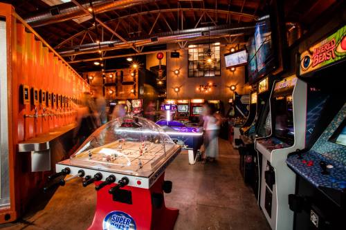 A vibrant arcade with various retro games, including air hockey and classic arcade machines, in a lively atmosphere.