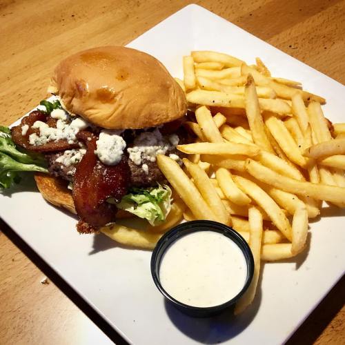 A juicy burger with bacon, lettuce, and blue cheese, served with a side of crispy fries and ranch dressing.
