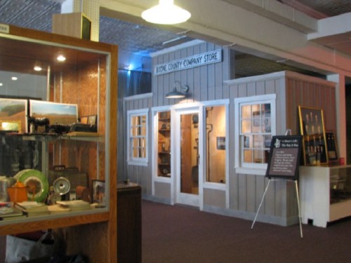 A replica of a historic company store with wooden exterior and display cases inside a museum setting.