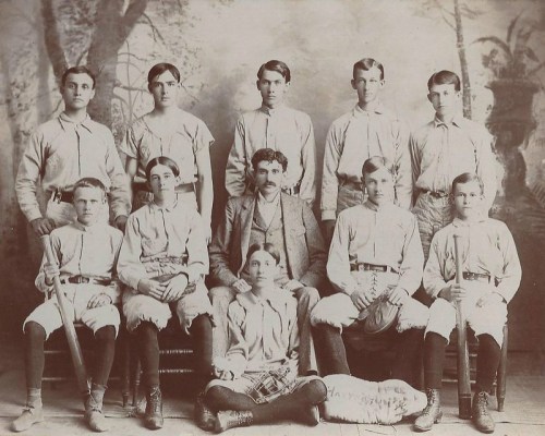 A vintage black-and-white photo of a 19th-century baseball team, posing with bats and gloves.