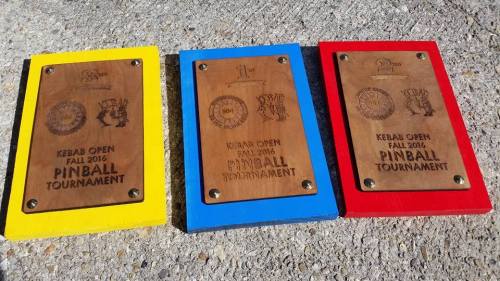 Three wooden plaques for the Kebab Open Fall 2016 Pinball Tournament, each with different colored borders: yellow, blue, and red.